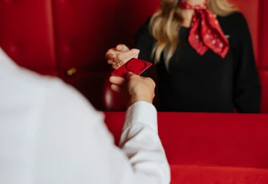 Eine Casinos Mitarbeiterin übergibt einer Kunde am Empfang mit ihrer rechten Hand eine Glücks Card Red.