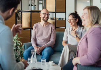 Zwei Männer und zwei Frauen sitzen an einem Kaffeetisch beisammen und lachen